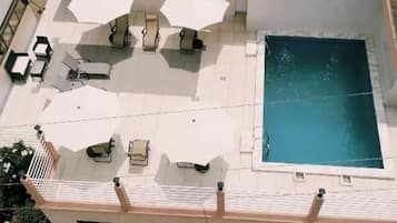Ein Pool auf dem Dach mit Liegestühlen und einer kleinen Terrasse.