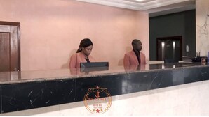 Un comptoir d’accueil dans un hôtel, avec un plan de travail en marbre et un logo au centre.