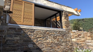 Ein Steinhaus mit einem großen Fenster und Holzläden.