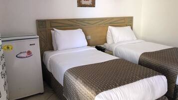 A hotel room with two beds, a refrigerator, and a wall-mounted picture.