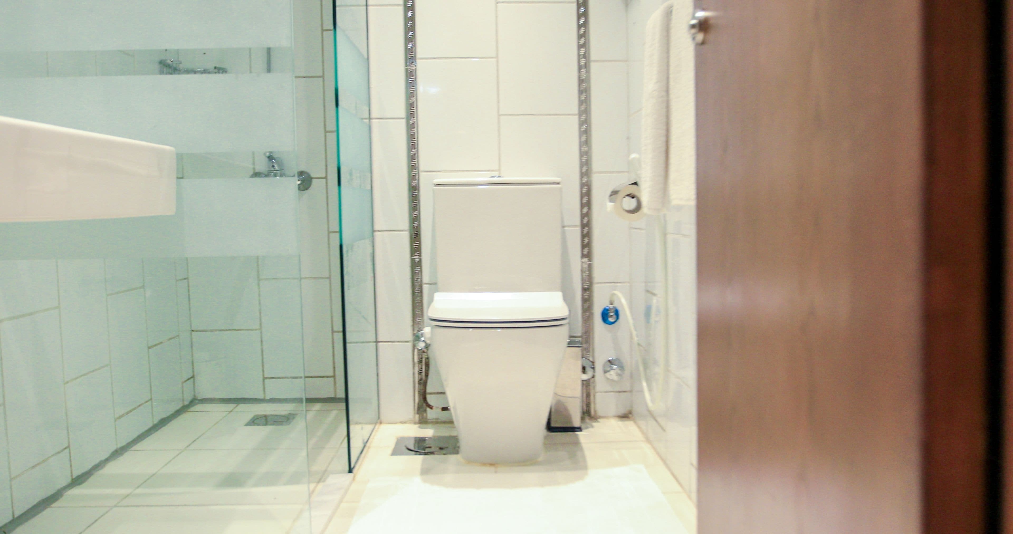 A bathroom with a glass shower enclosure, a toilet, and a sink.