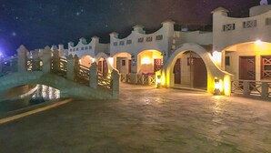 A nighttime view of a historic building with arched doorways and a stone bridge. - Green Leaves Aqua Park Beach Resort North Coast (Al-Hammam)