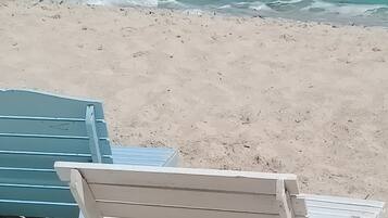 Een strand met een witte ligstoel en een blauwe ligstoel.