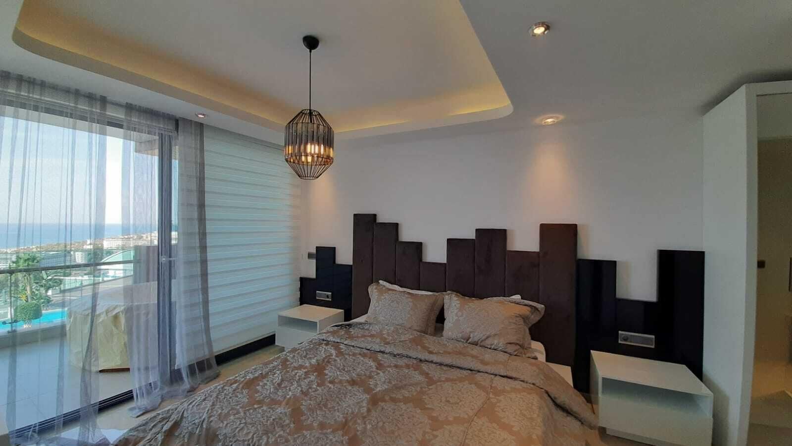 A modern bedroom with a large bed, a view of the city, and a balcony.