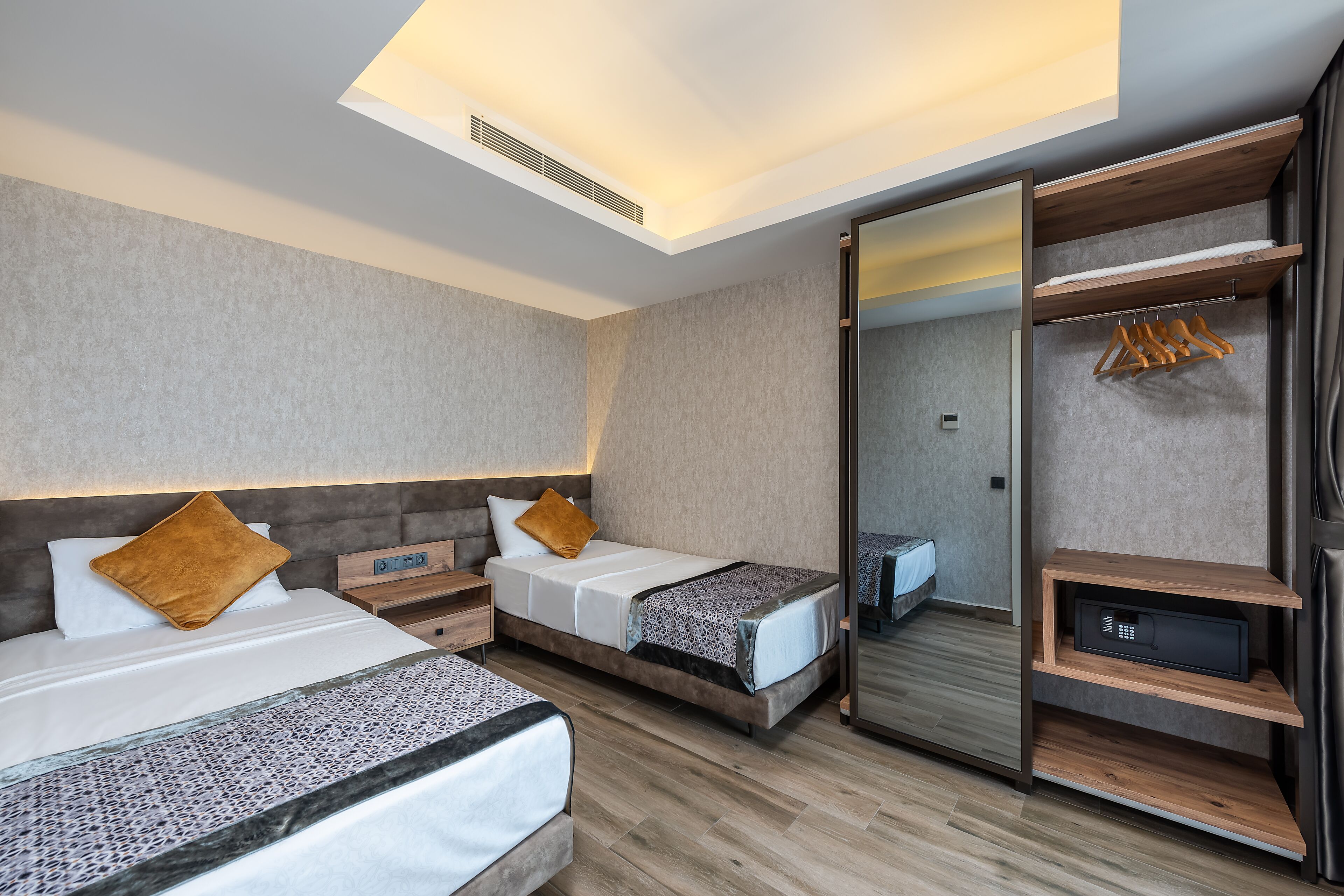 Una habitación de hotel moderna con dos camas, un armario y un espejo.