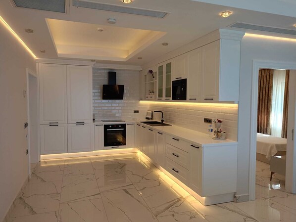 Una cocina moderna con armarios blancos, horno integrado y una encimera elegante.