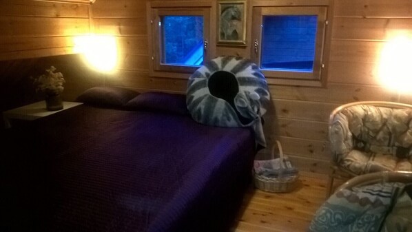 Una habitación acogedora con una cama, una silla y un ventanal con vistas al exterior.