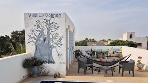Una piscina con un affresco raffigurante un albero, mobili da esterno e vista sulla zona circostante.