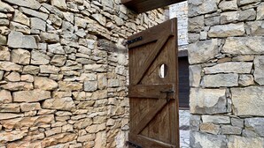 A rustic stone wall with a wooden door featuring a cross design.