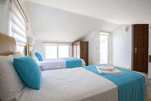 Une chambre d’hôtel avec deux lits, une fenêtre, une porte et un ventilateur de plafond.