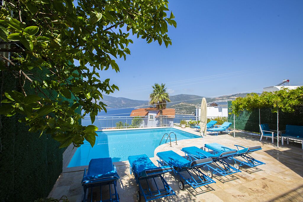 A pool area with lounge chairs and a view of mountains.