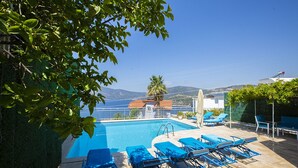 Un espace piscine avec des chaises longues et une vue sur les montagnes.