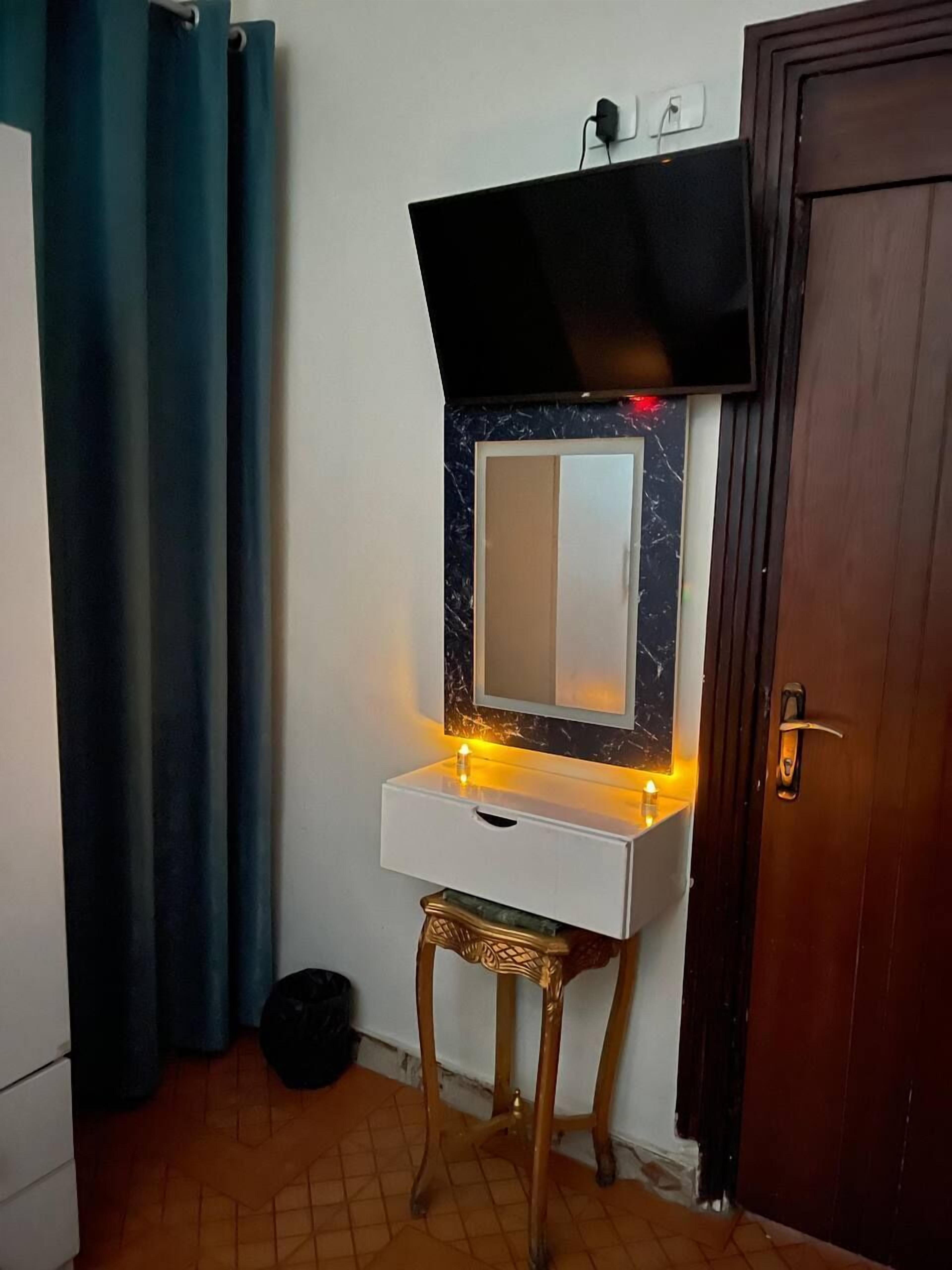 Ein gemütlicher Raum mit Schminktisch, Spiegel und einem an der Wand montierten Fernseher.