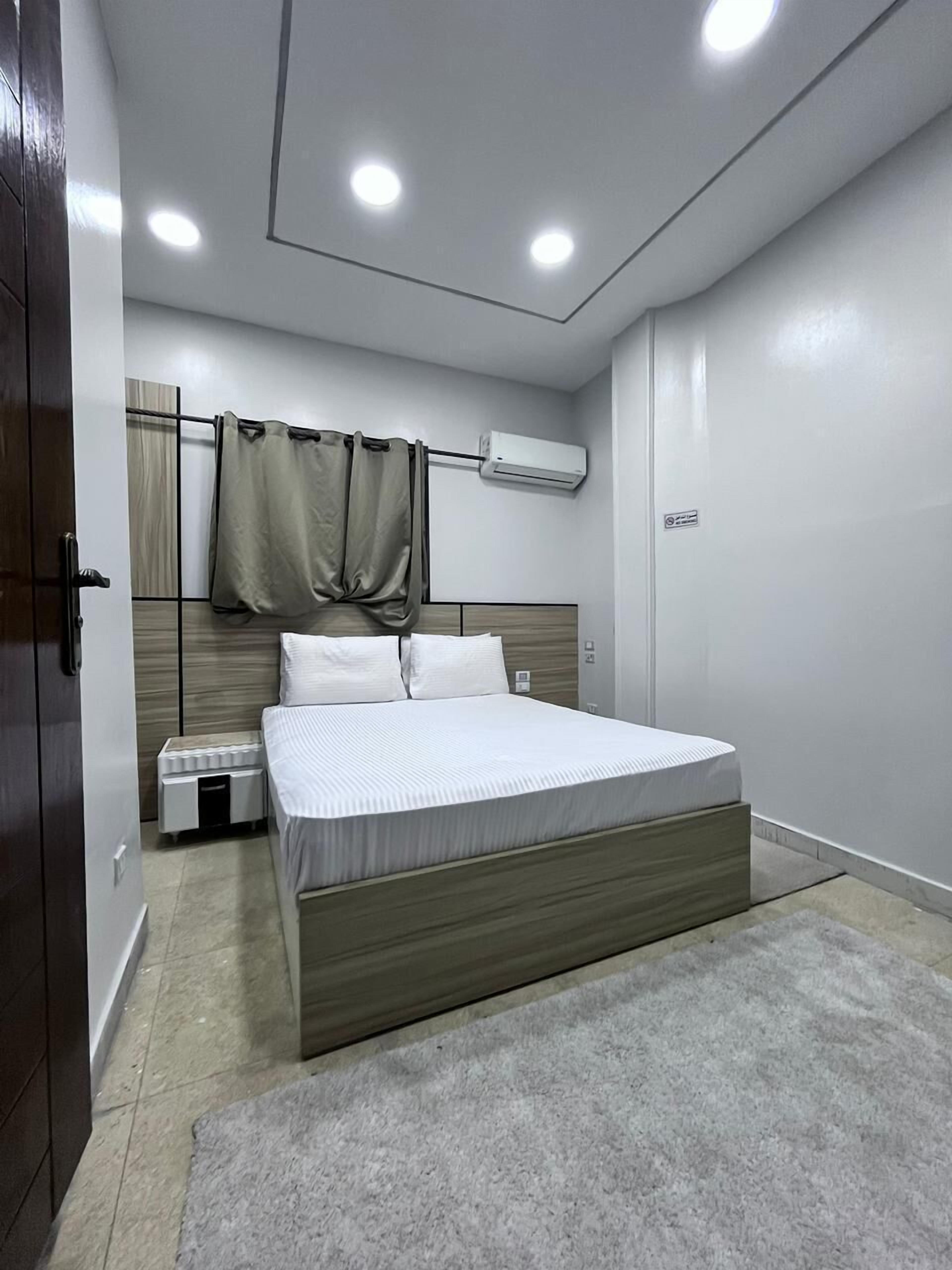 Un dormitorio moderno con una cama grande, un equipo de aire acondicionado y una mesita de noche pequeña.