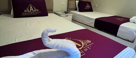 A hotel room with two beds, each with a headboard and a pillow with a logo. A towel is placed on the bed in front of the first bed.