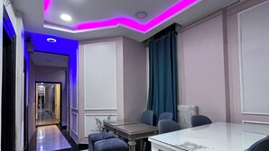 Ein moderner Essbereich mit weißem Tisch und Stühlen, einer blauen Akzentwand und einem Gang zu einem weiteren Raum.