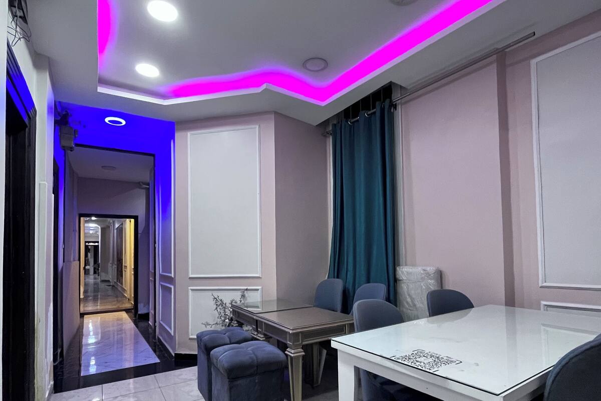A modern dining area with a white table and chairs, a blue accent wall, and a hallway leading to another room.