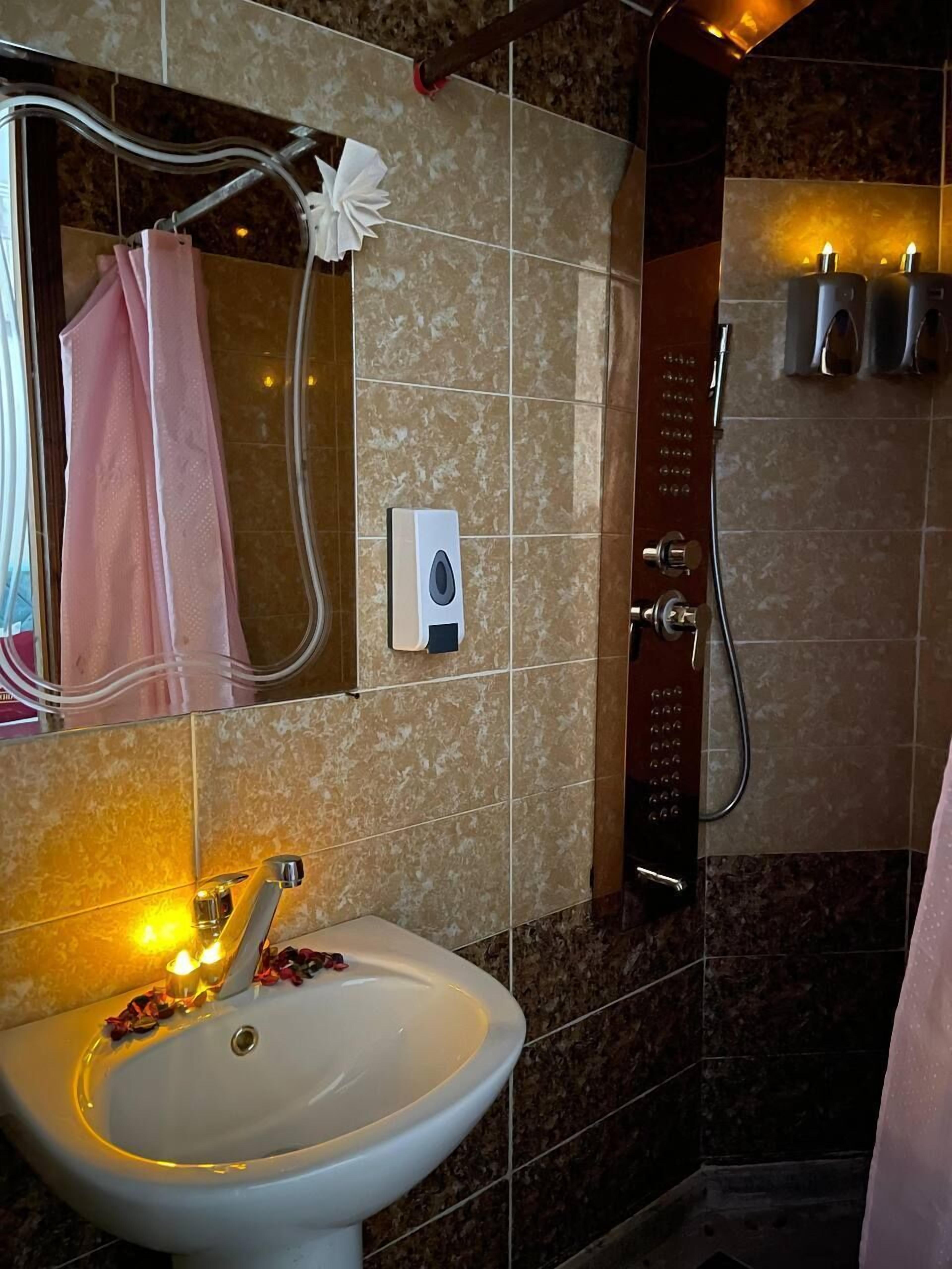 Casa de banho com lavatório, espelho, porta-toalhas e chuveiro.