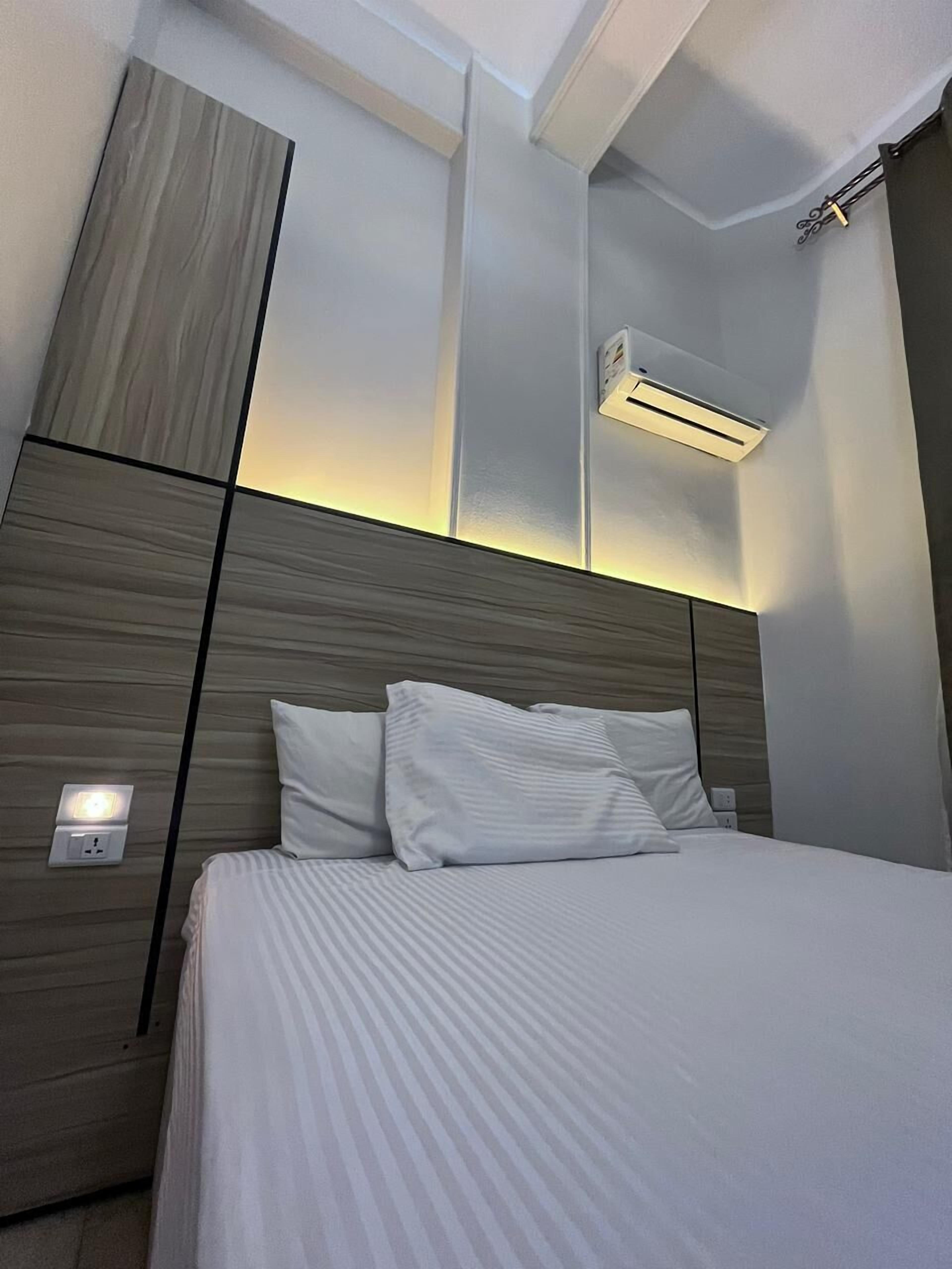 Une chambre d’hôtel moderne avec un grand lit, un climatiseur fixé au mur et un interrupteur sur le mur.