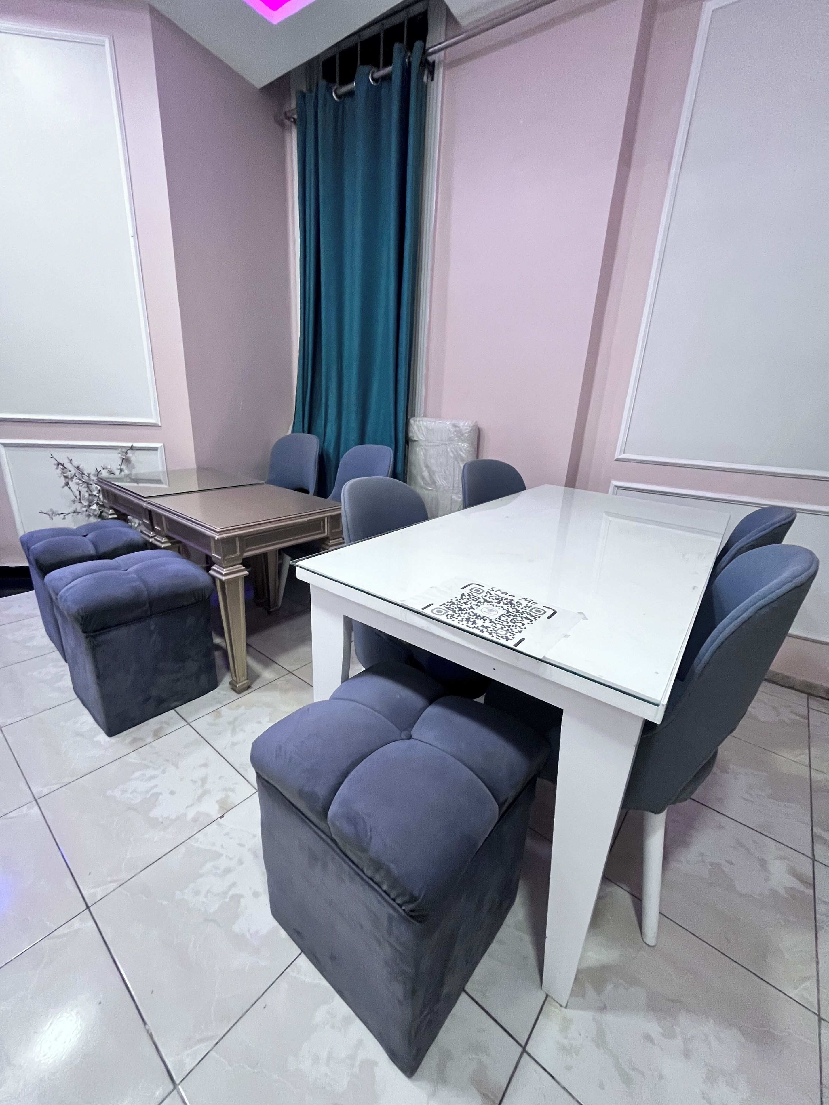Een vergaderruimte met een witte tafel, blauwe stoelen en bijpassende poefs.