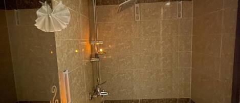 Een badkamer met een douche, een wastafel en een spiegel.