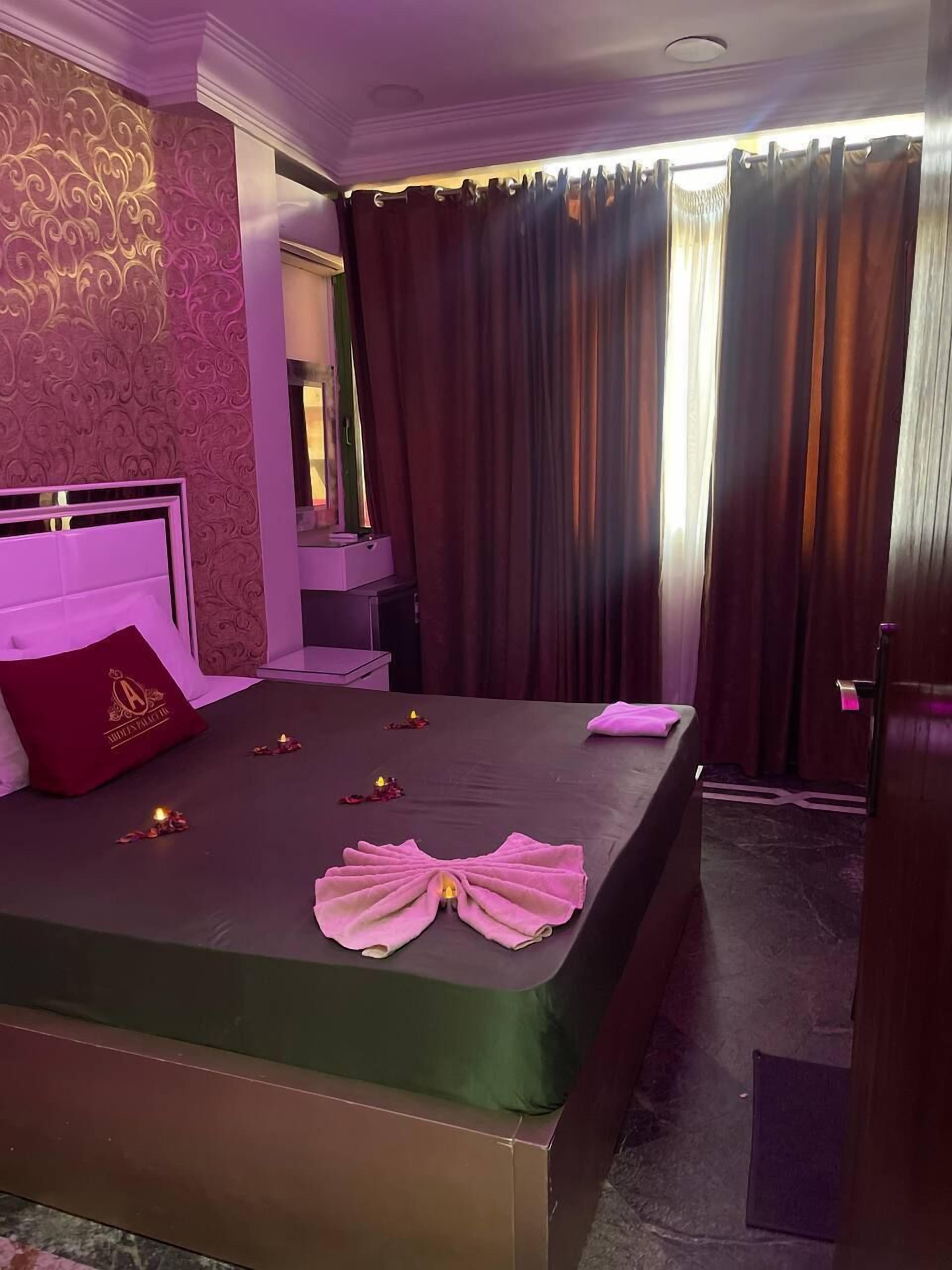 A hotel room with a large bed, a vanity with a mirror, and a view of the outside through curtains.