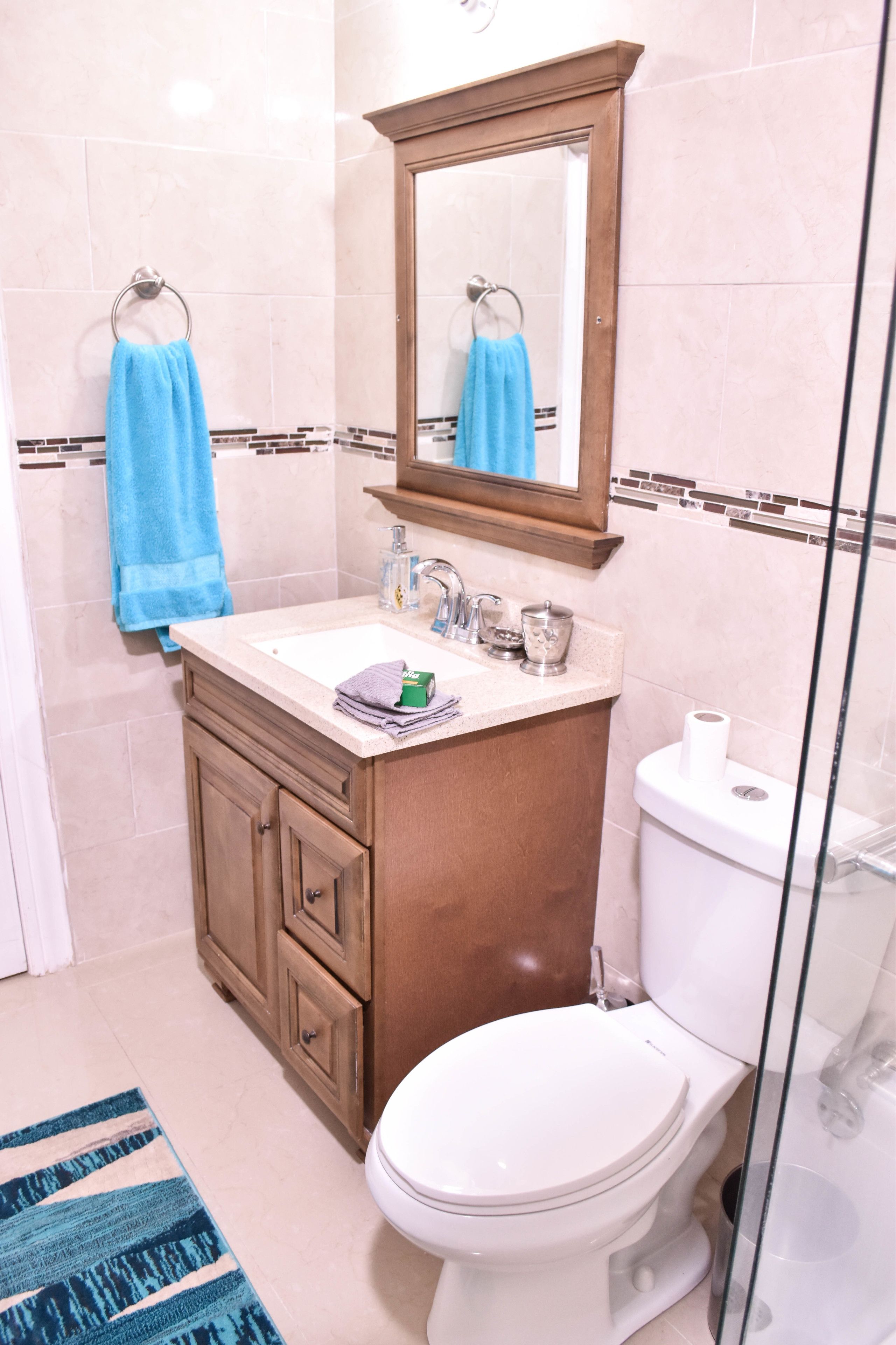 Une salle de bain équipée d’un lavabo, d’un miroir, de toilettes et d’une douche à parois en verre.