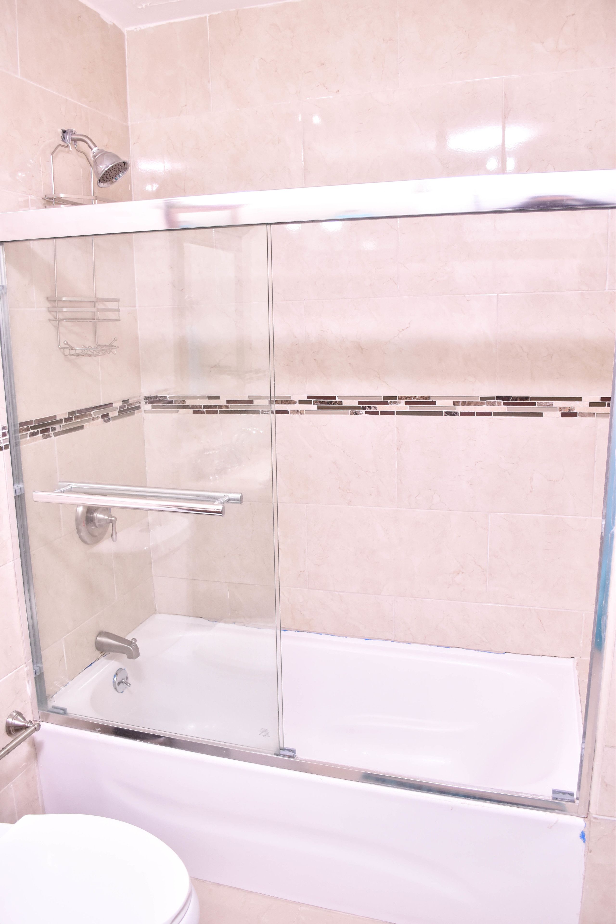 Ein Badezimmer mit einer gläsernen Duschkabine, einer weißen Badewanne und einem WC.