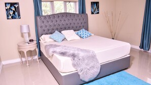 Ein Schlafzimmer mit einem großen Bett, einem Nachttisch, einer Lampe und Bildern an den Wänden.