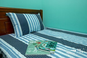 Una cama con ropa de cama a rayas, una almohada, un libro y una revista encima.