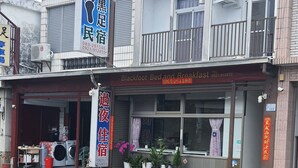 A building with a sign for 'Blackfoot Bed and Breakfast' and a large blue sign with Chinese characters. - Blackfoot Homestay (Taitung)