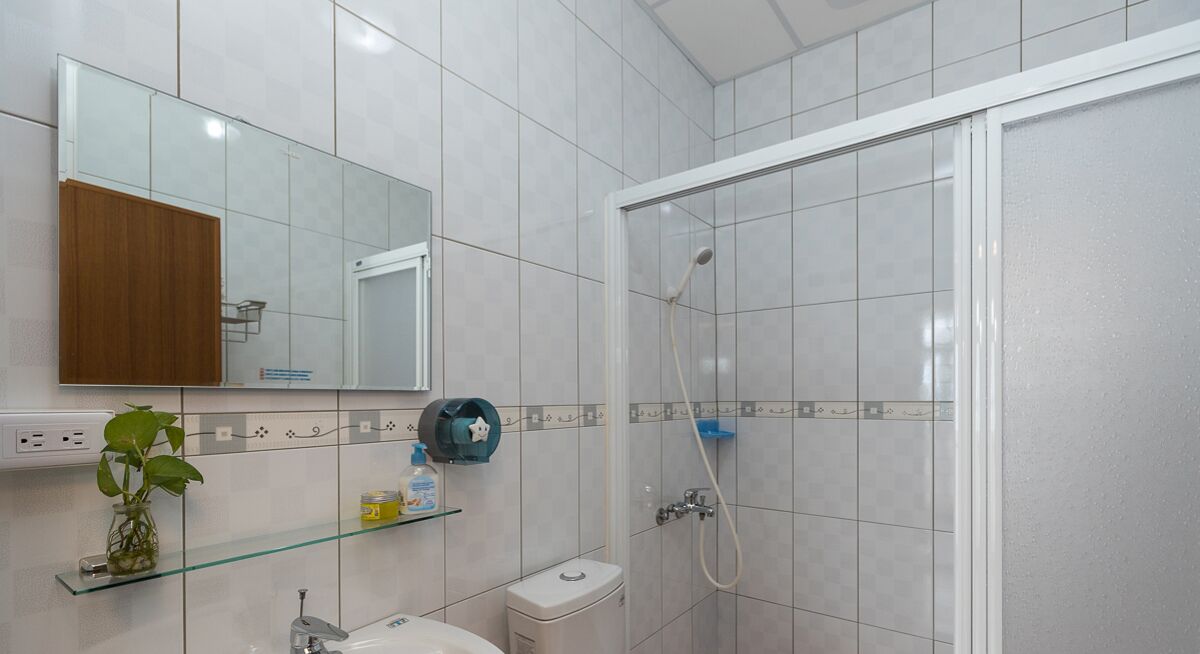 Un baño moderno con cabina de ducha de vidrio, un lavamanos con espejo y un inodoro.