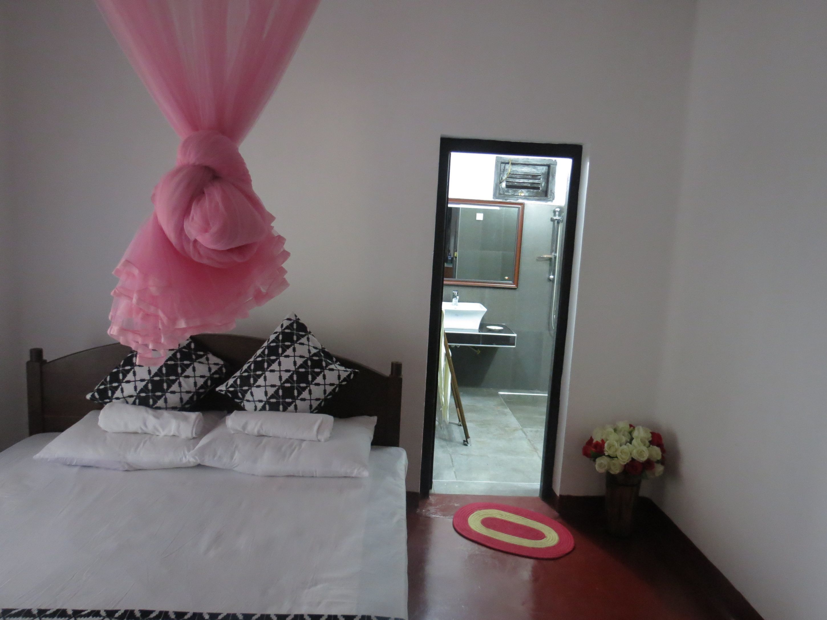 A hotel room with a bed, a mirror, and a bathroom visible through the door.
