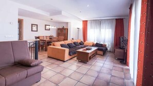 Un saló modern amb un sofà marró, una taula de centre i una zona de menjador amb taula i cadires.