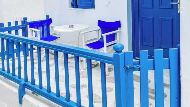 Un bâtiment blanc avec une porte bleue et une rambarde bleue.