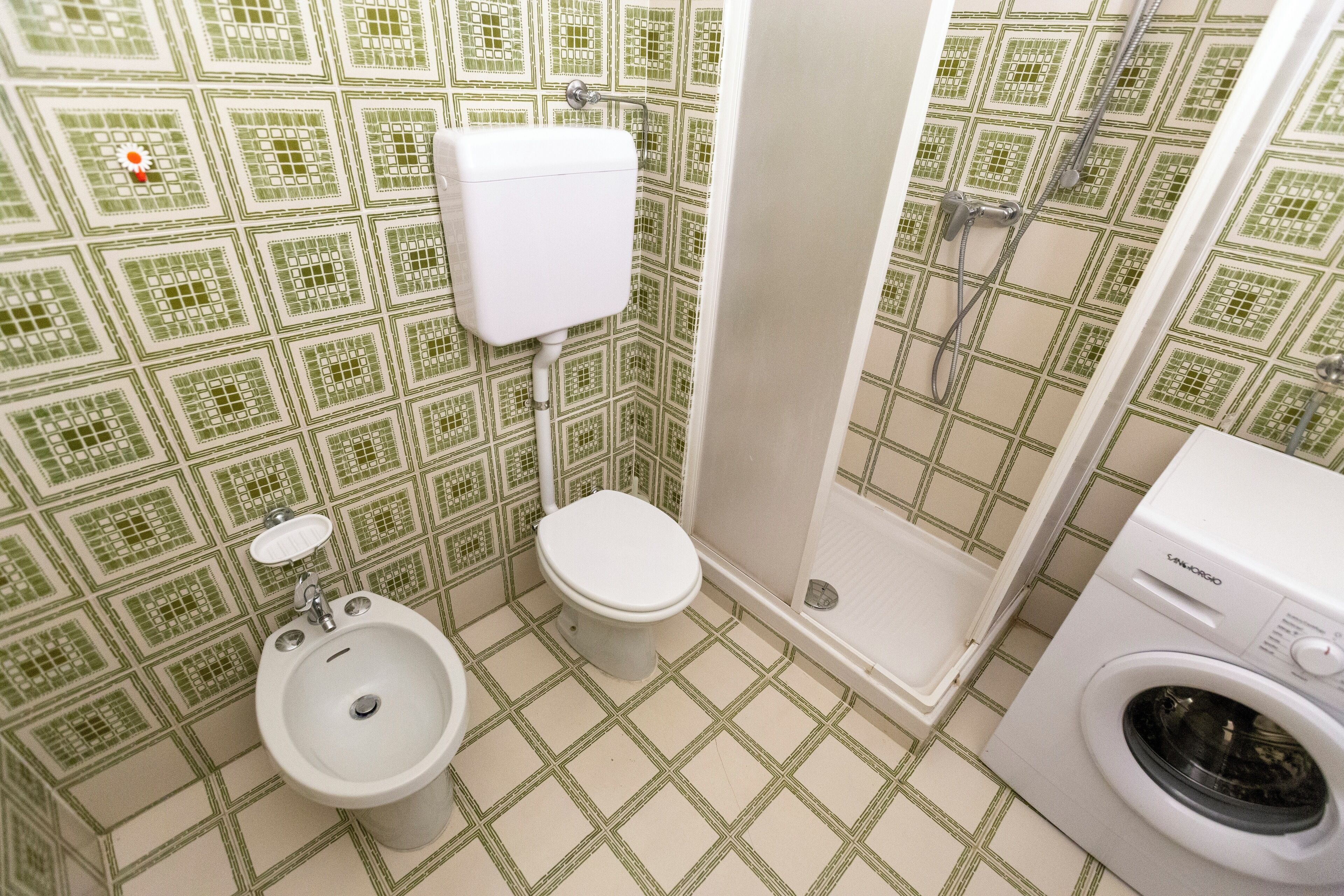 Un baño con inodoro, bidé, ducha y lavadora.
