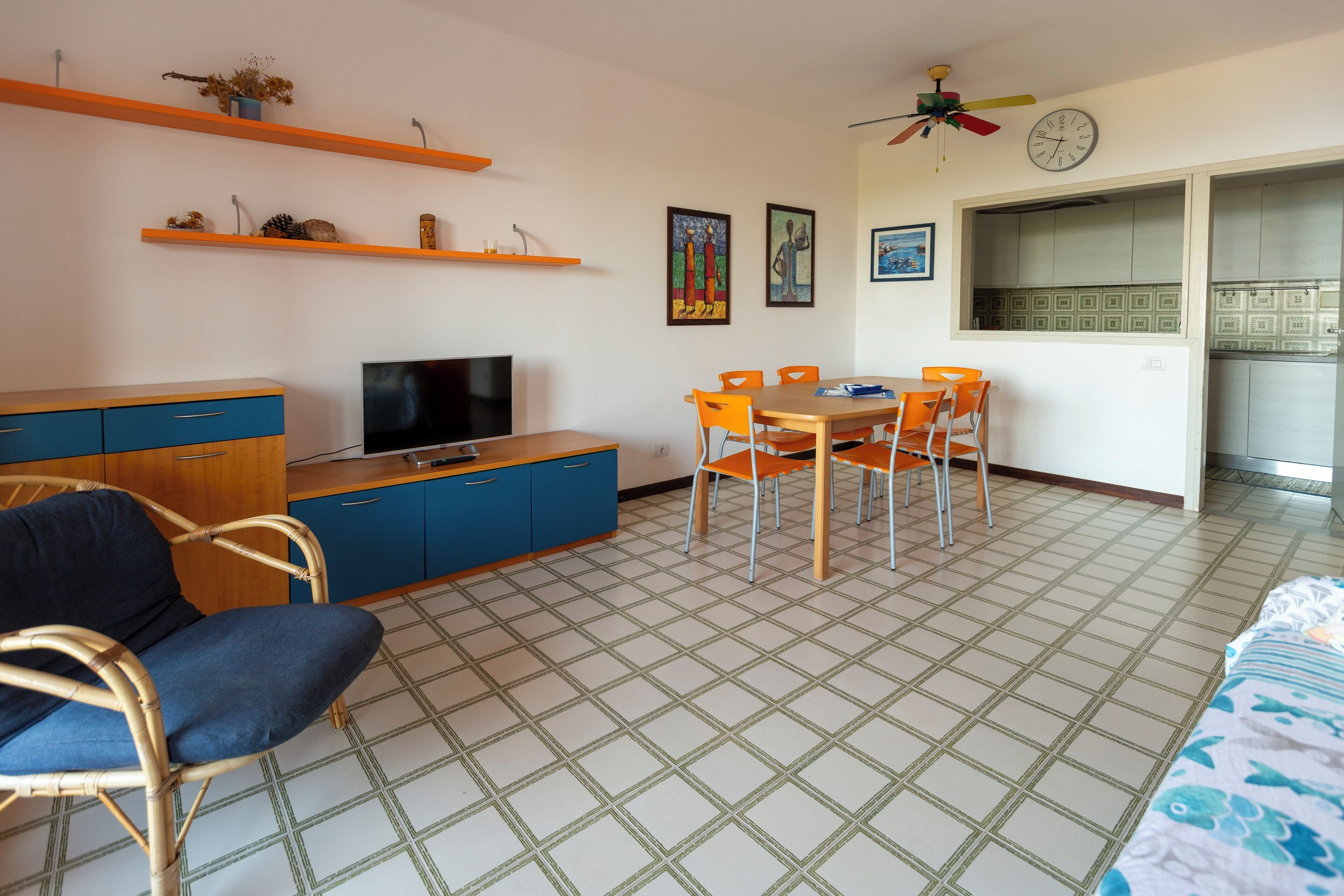 A compact living space with a television, dining table, chairs, and a sofa.