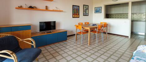 A compact living space with a television, dining table, chairs, and a sofa.