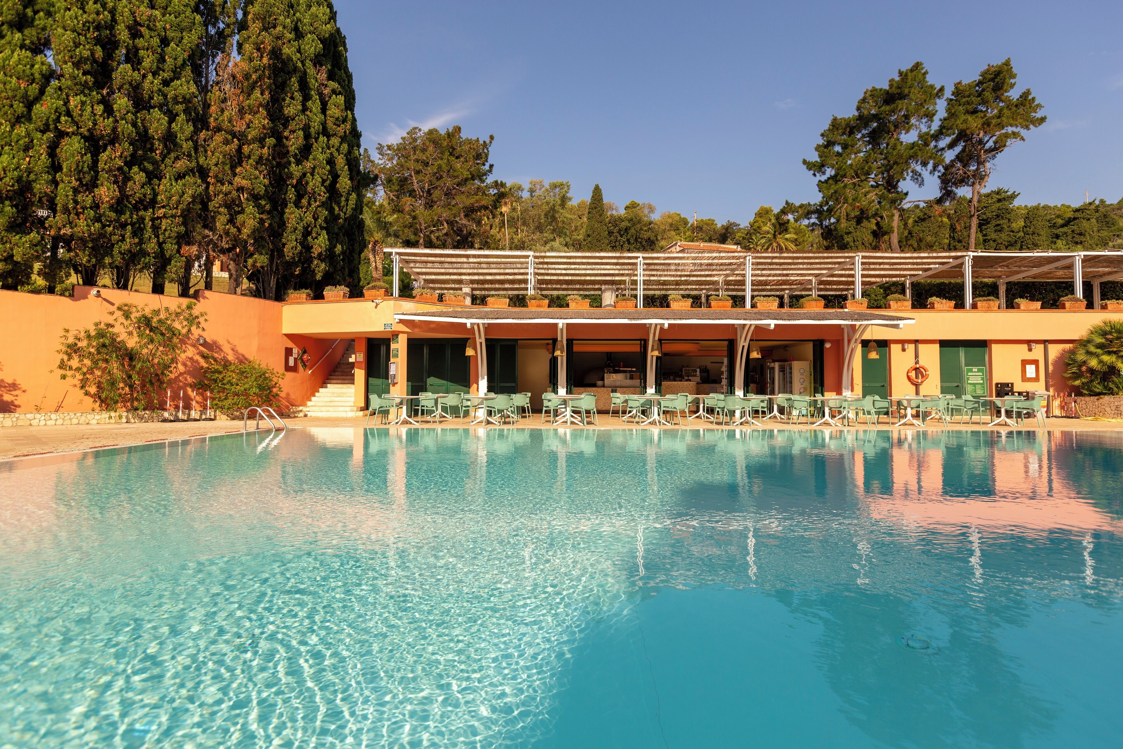 A swimming pool with a covered seating area and a staircase leading to an upper level.