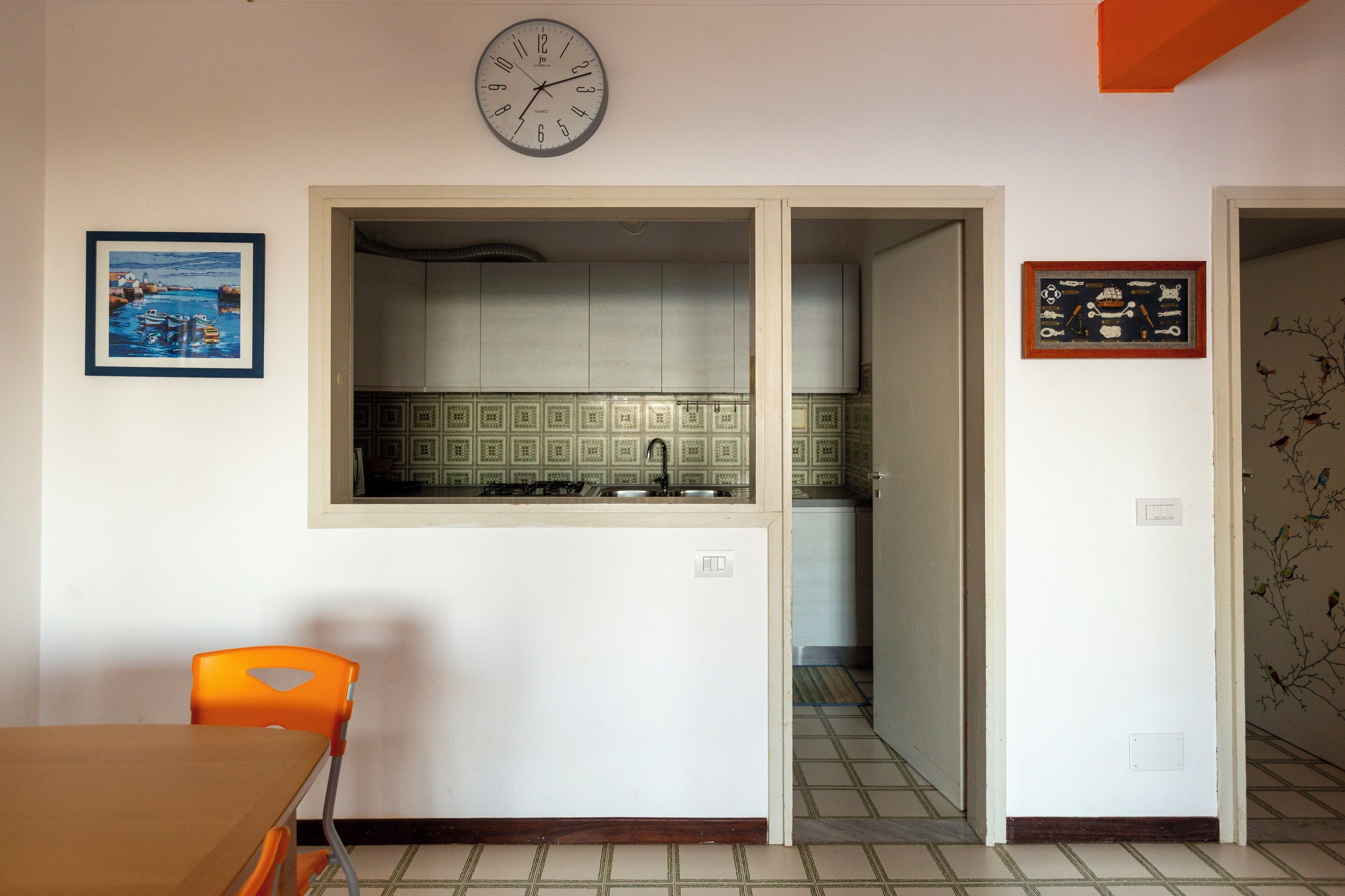 Eine Küche mit einer Uhr, einem gerahmten Bild und einer Fliesenküchenwand.