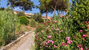 A stone staircase leading up a hill, surrounded by lush greenery and pink flowers. - Four-room apartment in the Capo D'Arco area with direct access to the sea (Rio Marina)