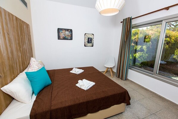A bedroom with a bed, a window with curtains, and two wall-mounted pictures.