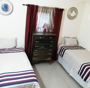 Une chambre avec deux lits, une commode et un miroir au mur.