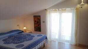 Une chambre à coucher avec un lit, une table de chevet, une lampe, un tableau et une fenêtre avec des rideaux.