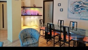 Un coin repas avec une table et des chaises en verre, une cuisine équipée d’un ventilateur et une porte avec une pancarte.