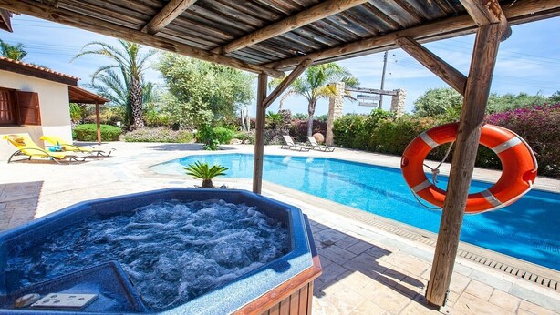 A pool area with a hot tub, lounge chairs, and a lifebuoy. - Spacious Villa, Large Private Pool, Outdoor Jacuzzi, Attractive Gardens, 10 min walk to the Beach! (Latchi)