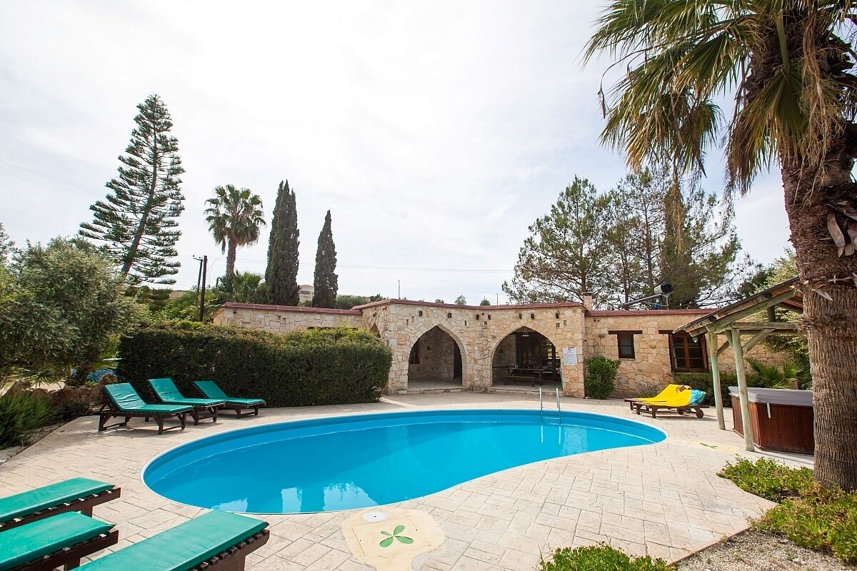 Une piscine avec des chaises longues, un jacuzzi et des arches en pierre.