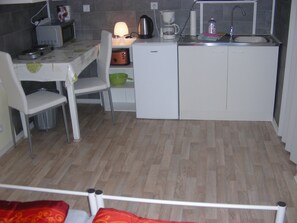 A compact kitchen with a microwave, coffee maker, and sink. There is a chair and a small table with a lamp. - Small holiday apartment next to Fulda Rhön Vogelsberg good central location Hesse up to 2 persons (Künzell)