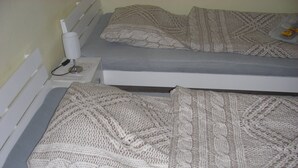 Una cama con un colchón gris y una manta tejida.
