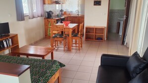 A spacious living area with a wooden ceiling, a dining table with chairs, a black sofa, and a TV on a wooden stand. - Bahari 1st floor mountain, sea and riviera view (3 p) (Morro)